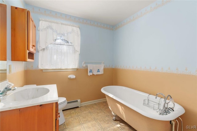 full bath featuring toilet, a baseboard heating unit, vanity, a freestanding tub, and baseboards