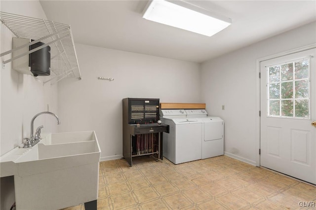 clothes washing area with light floors, washing machine and clothes dryer, a sink, laundry area, and baseboards