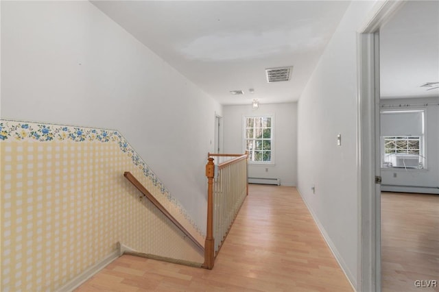 hall featuring a baseboard radiator, an upstairs landing, visible vents, baseboards, and light wood finished floors