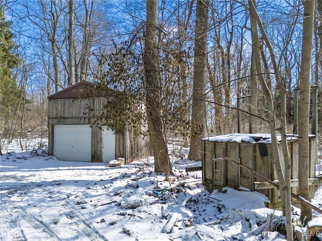 yard covered in snow with a detached garage and an outdoor structure