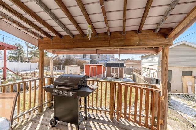 wooden terrace with an outbuilding, a shed, grilling area, and a fenced backyard