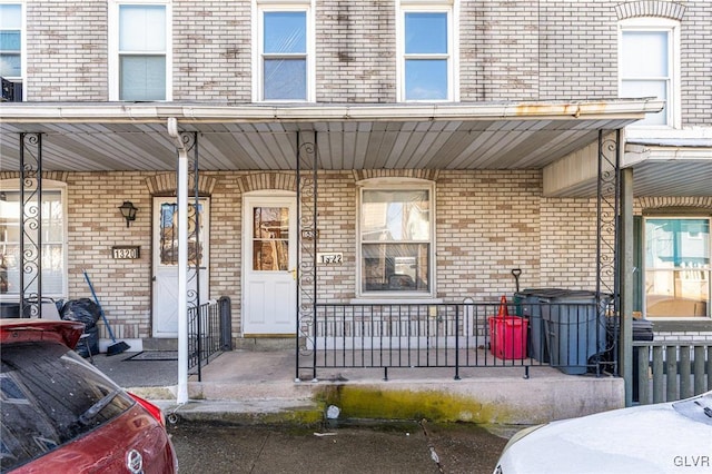 view of exterior entry featuring a porch and brick siding