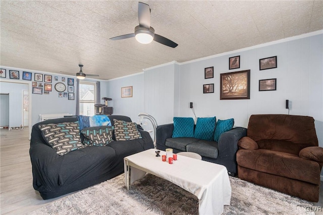 living area with light wood-style flooring, a textured ceiling, ceiling fan, and crown molding