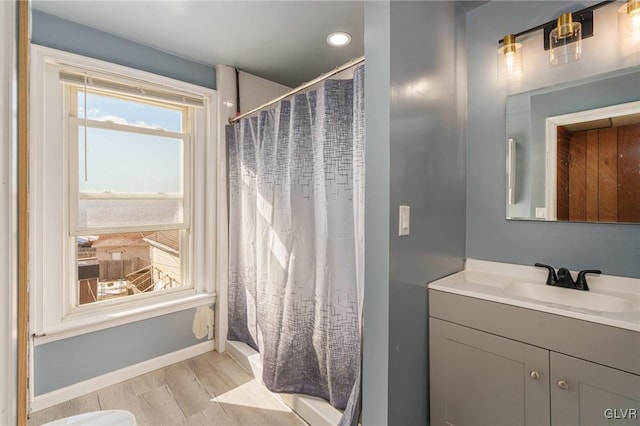 full bathroom featuring baseboards, wood finished floors, and vanity