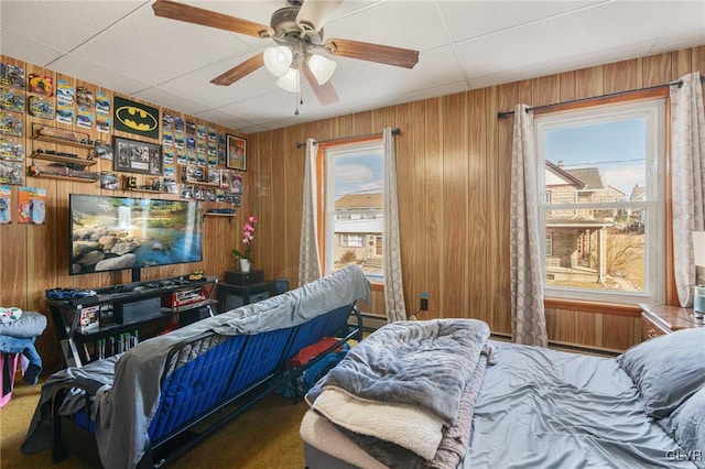 bedroom with carpet flooring, a ceiling fan, and wooden walls