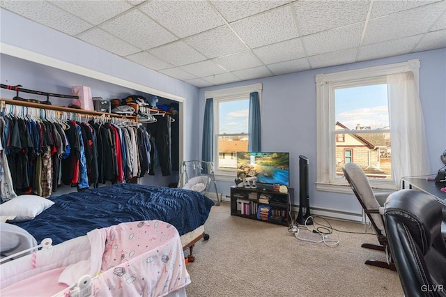 bedroom featuring a paneled ceiling, a closet, carpet flooring, and baseboard heating