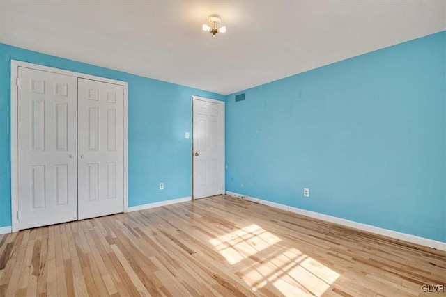 unfurnished bedroom featuring baseboards, visible vents, and light wood-style floors