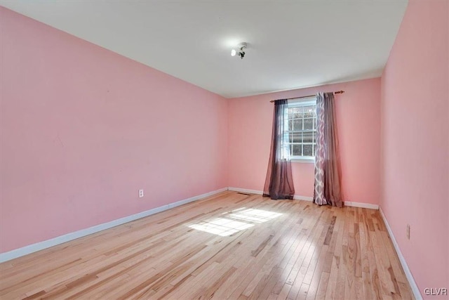 spare room with baseboards and light wood-style floors