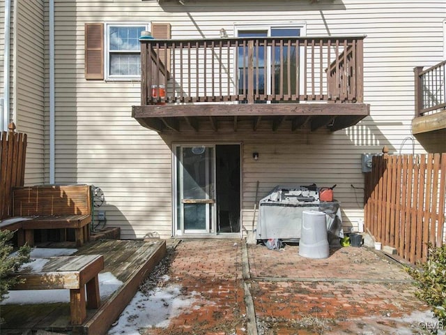 rear view of property with a balcony, a patio area, and fence