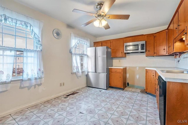 kitchen with a ceiling fan, brown cabinets, stainless steel appliances, light countertops, and a sink