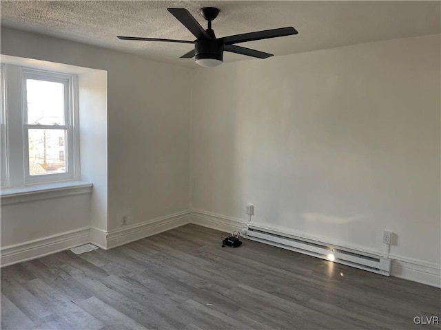 unfurnished room featuring a textured ceiling, baseboard heating, wood finished floors, and baseboards