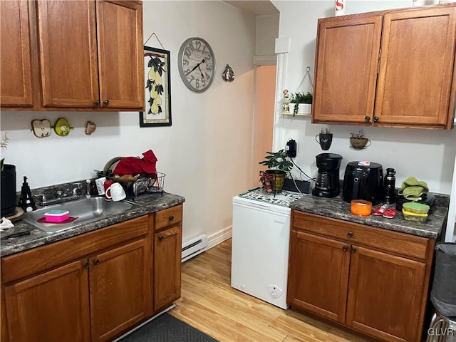 kitchen featuring a baseboard radiator, brown cabinets, and a sink