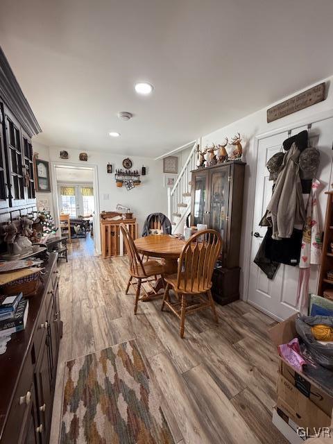 dining room with light wood finished floors, stairway, and recessed lighting