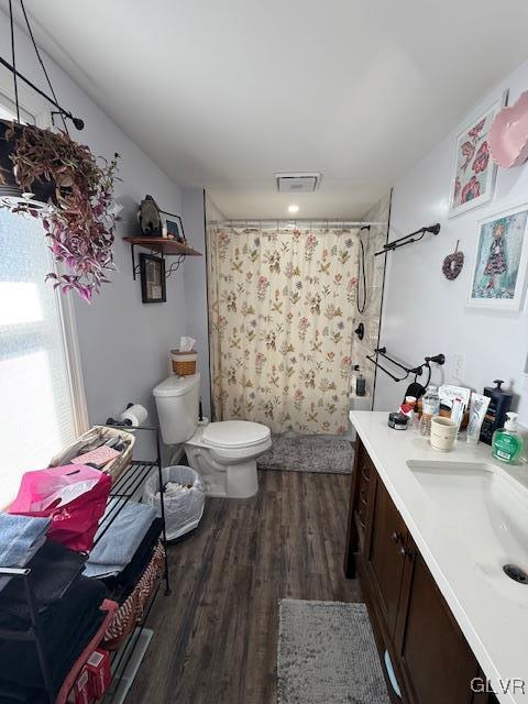 bathroom featuring toilet, a shower with shower curtain, wood finished floors, vanity, and visible vents