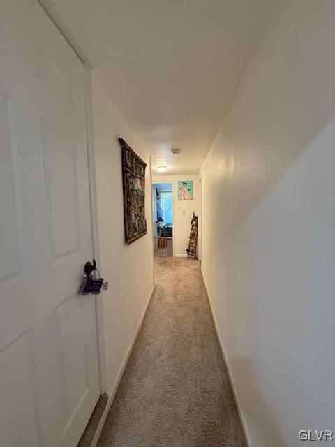 corridor featuring light carpet and baseboards