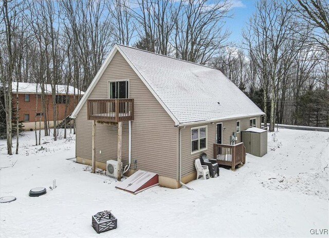 snow covered house featuring a garage and ac unit