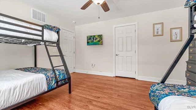 bedroom with visible vents, ceiling fan, baseboards, and wood finished floors