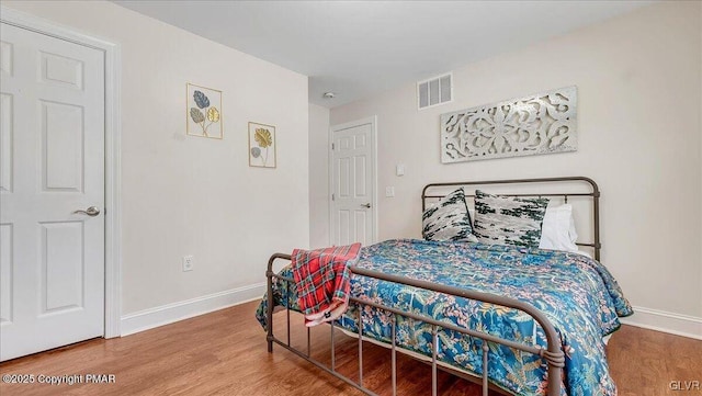 bedroom with visible vents, baseboards, and wood finished floors