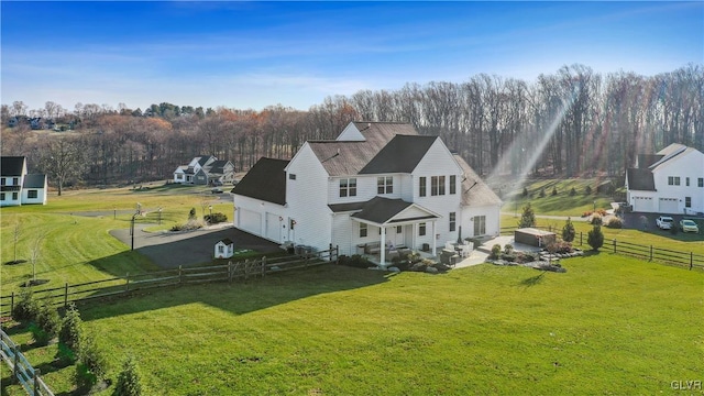 back of house with a garage, a lawn, aphalt driveway, a rural view, and fence