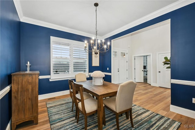 dining area featuring baseboards, ornamental molding, a notable chandelier, and wood finished floors