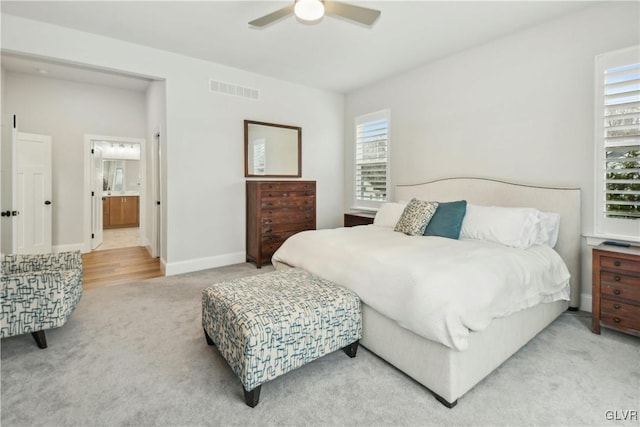 bedroom featuring baseboards, visible vents, a ceiling fan, ensuite bathroom, and carpet floors