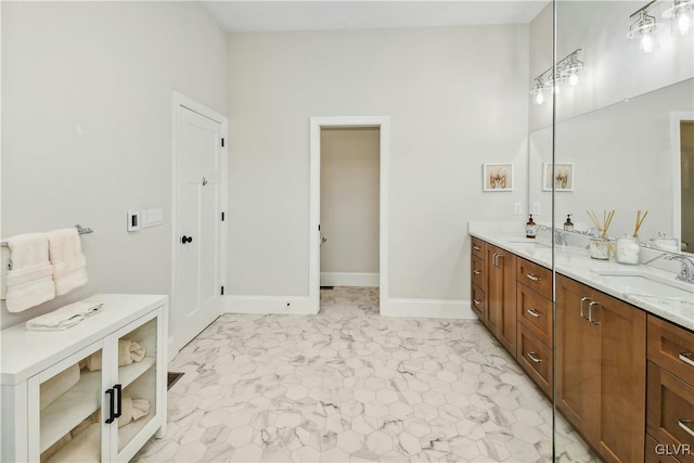 full bathroom featuring double vanity, baseboards, and a sink