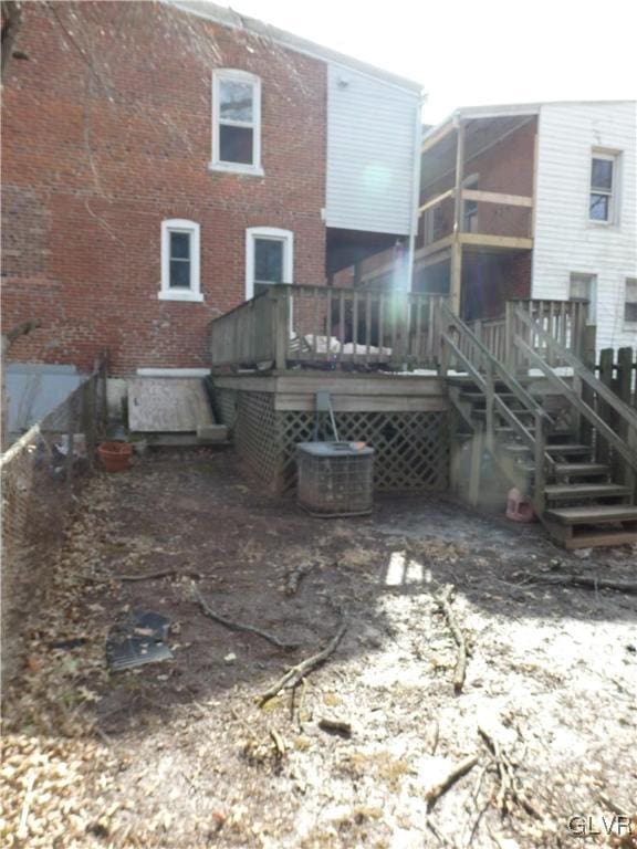 back of house with stairs, brick siding, and a wooden deck