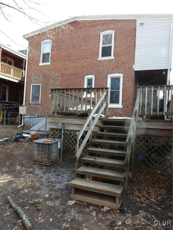 back of house featuring central air condition unit, stairway, and brick siding