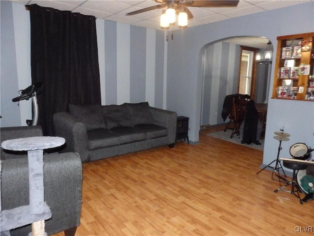 living area featuring a paneled ceiling, arched walkways, and wood finished floors