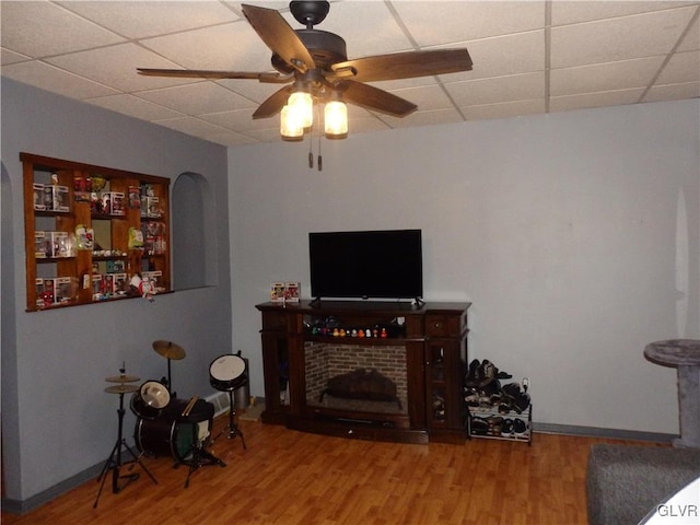 living area with wood finished floors, a paneled ceiling, and a ceiling fan