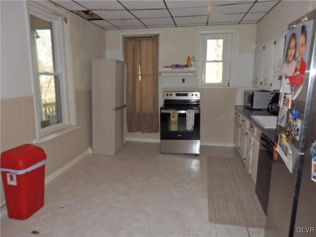 kitchen featuring appliances with stainless steel finishes, white cabinets, under cabinet range hood, and a drop ceiling