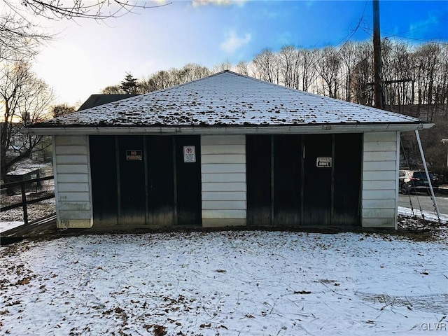 snow covered garage featuring fence