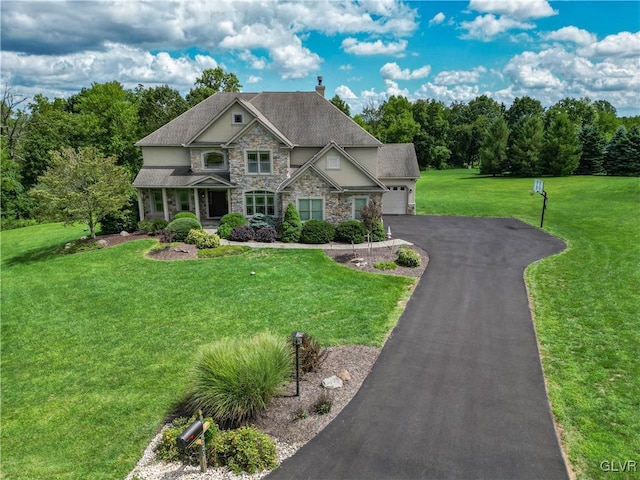 view of front facade with stone siding, aphalt driveway, a chimney, and a front lawn