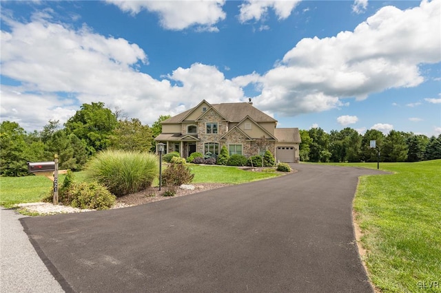 view of front facade with stone siding, a front lawn, and driveway