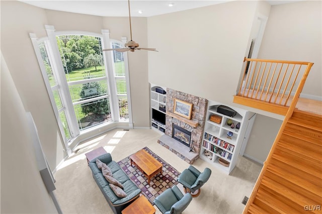 living area with ceiling fan, a stone fireplace, and baseboards