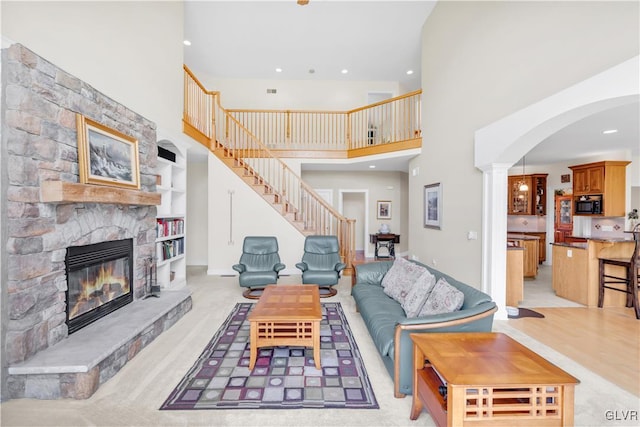 living area with arched walkways, a fireplace, decorative columns, recessed lighting, and stairway