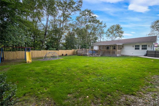 view of yard featuring a deck, a playground, and a fenced backyard