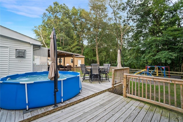 deck with an outdoor pool, outdoor dining area, and a playground