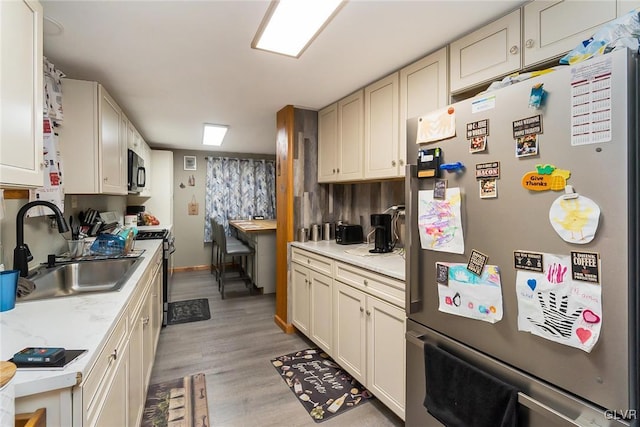 kitchen with appliances with stainless steel finishes, light wood-type flooring, and a sink