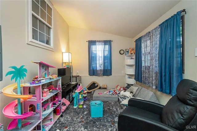 recreation room featuring lofted ceiling and wainscoting