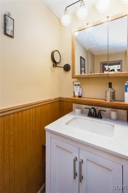 bathroom featuring a wainscoted wall, wood walls, and vanity