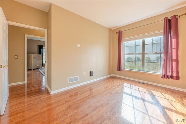 spare room with light wood-style floors, baseboards, and visible vents