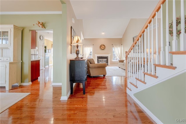 foyer entrance featuring stairway, a fireplace, light wood-style flooring, and baseboards