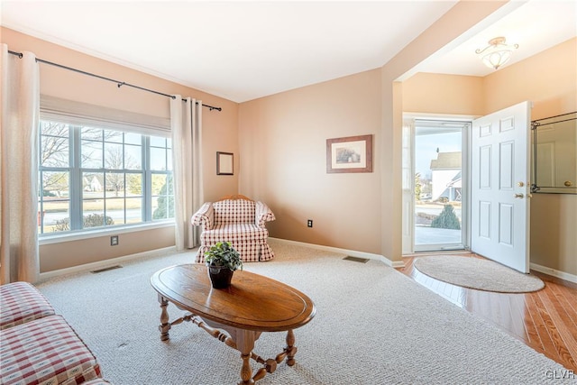 living area with light wood-type flooring, visible vents, and baseboards