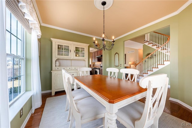 dining space featuring an inviting chandelier, ornamental molding, wood finished floors, baseboards, and stairs