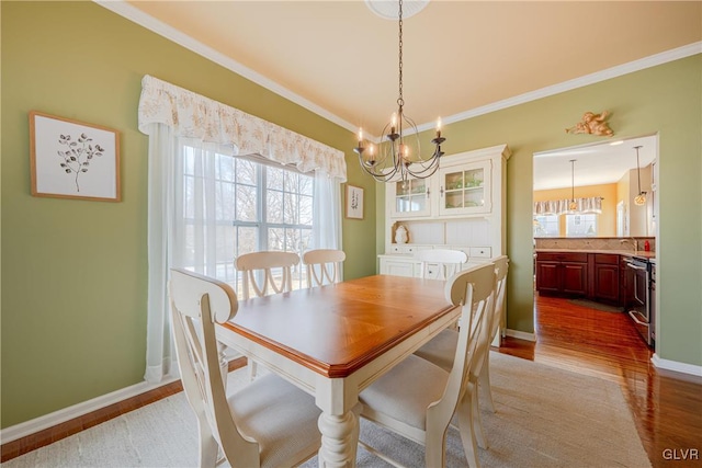 dining room with crown molding, light wood-style flooring, baseboards, and an inviting chandelier