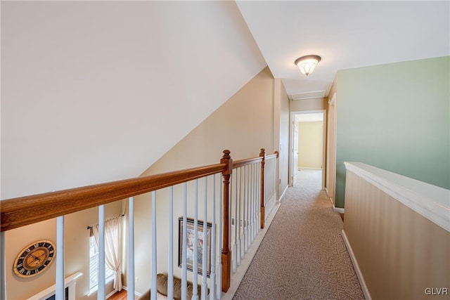 corridor featuring light carpet, lofted ceiling, and baseboards