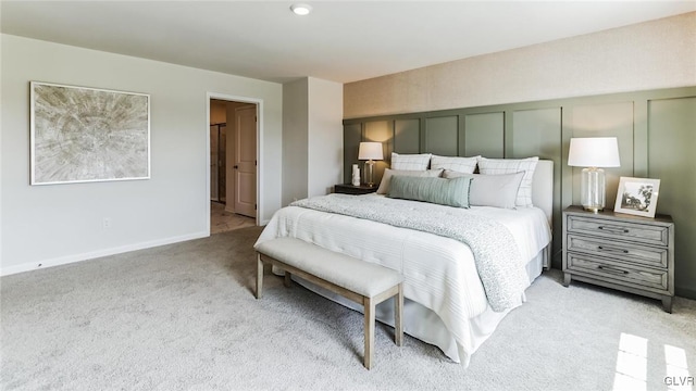 bedroom featuring light carpet, baseboards, and a decorative wall