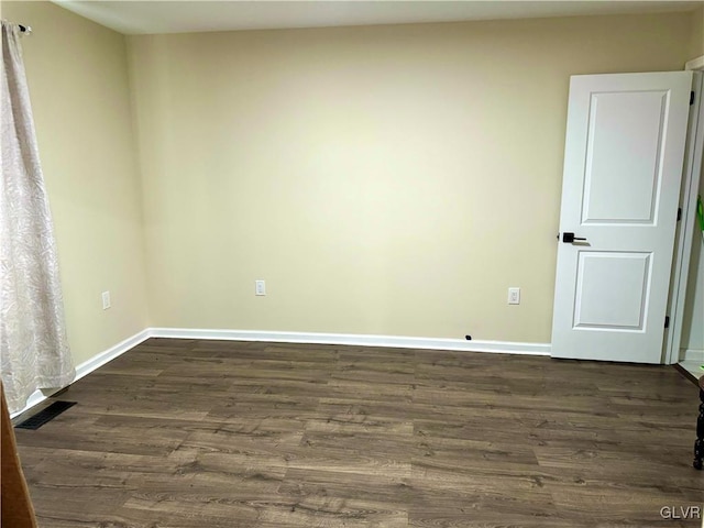 unfurnished room with baseboards, visible vents, and dark wood finished floors