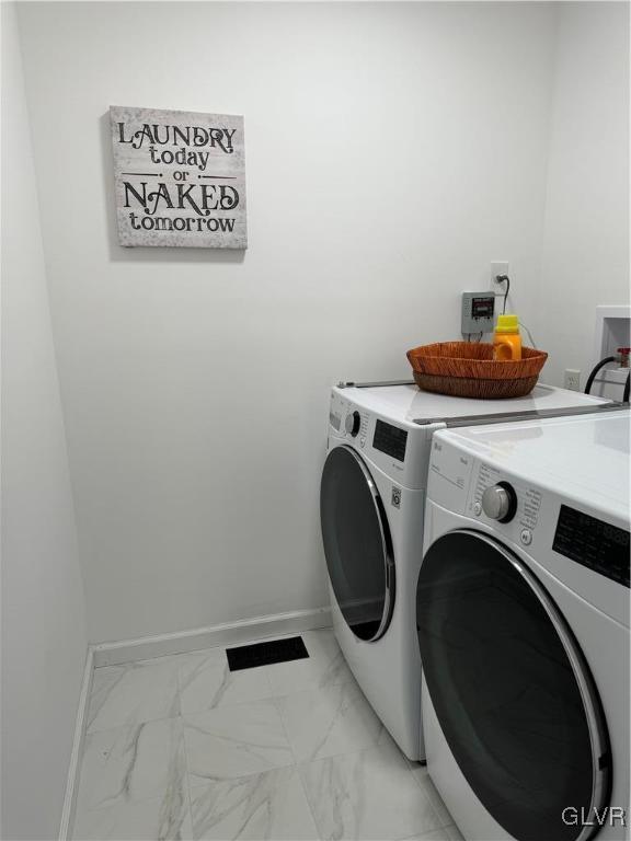 clothes washing area featuring washer and dryer, laundry area, marble finish floor, and baseboards